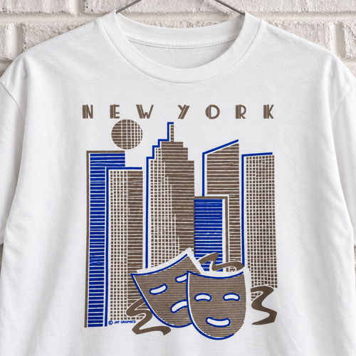 White New York skyline and theatre masks graphic tee on a white brick wall with a wire hanger — close-up front view