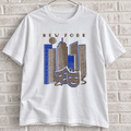 White New York skyline and theatre masks graphic tee on a white brick wall with a wire hanger — front view