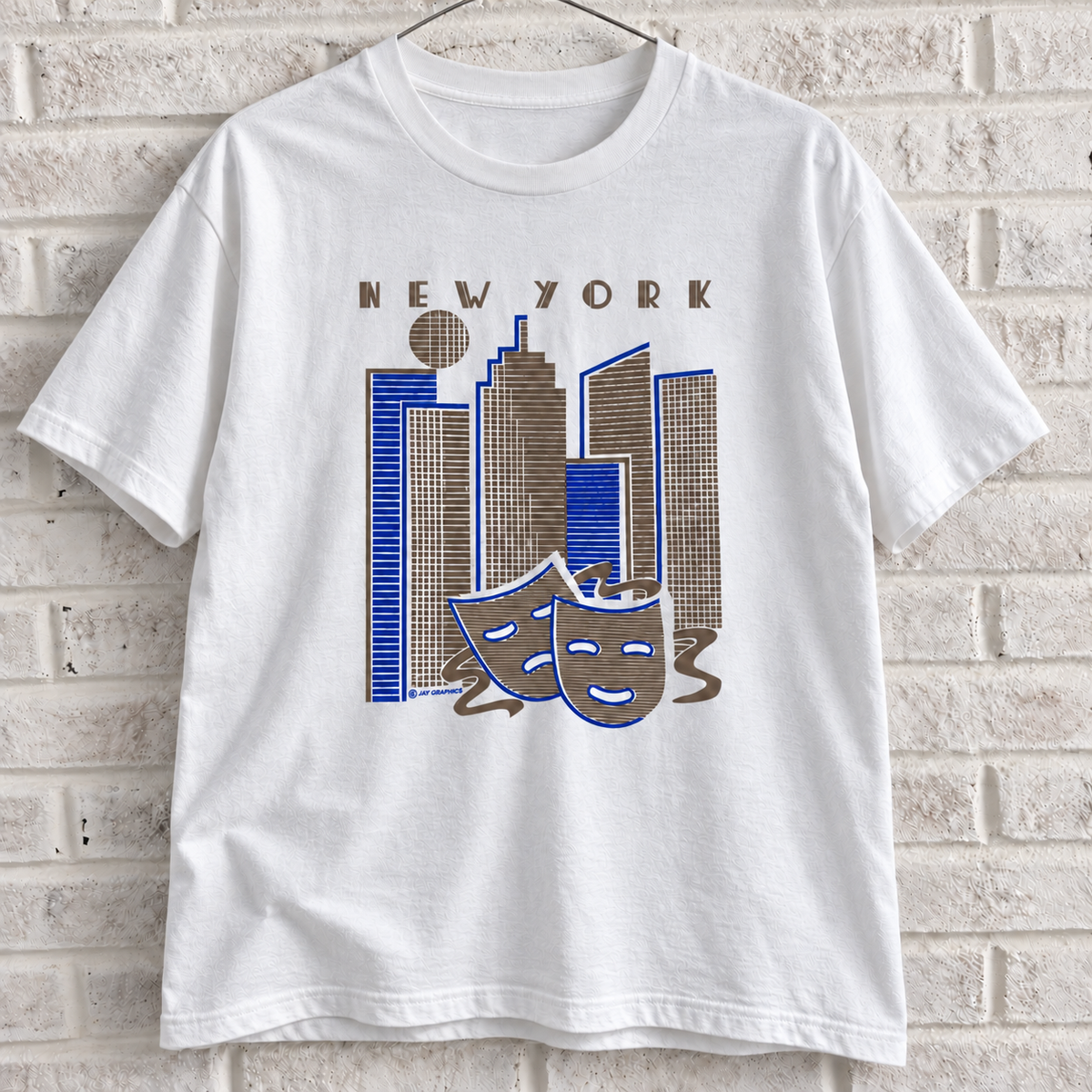 White New York skyline and theatre masks graphic tee on a white brick wall with a wire hanger — front view