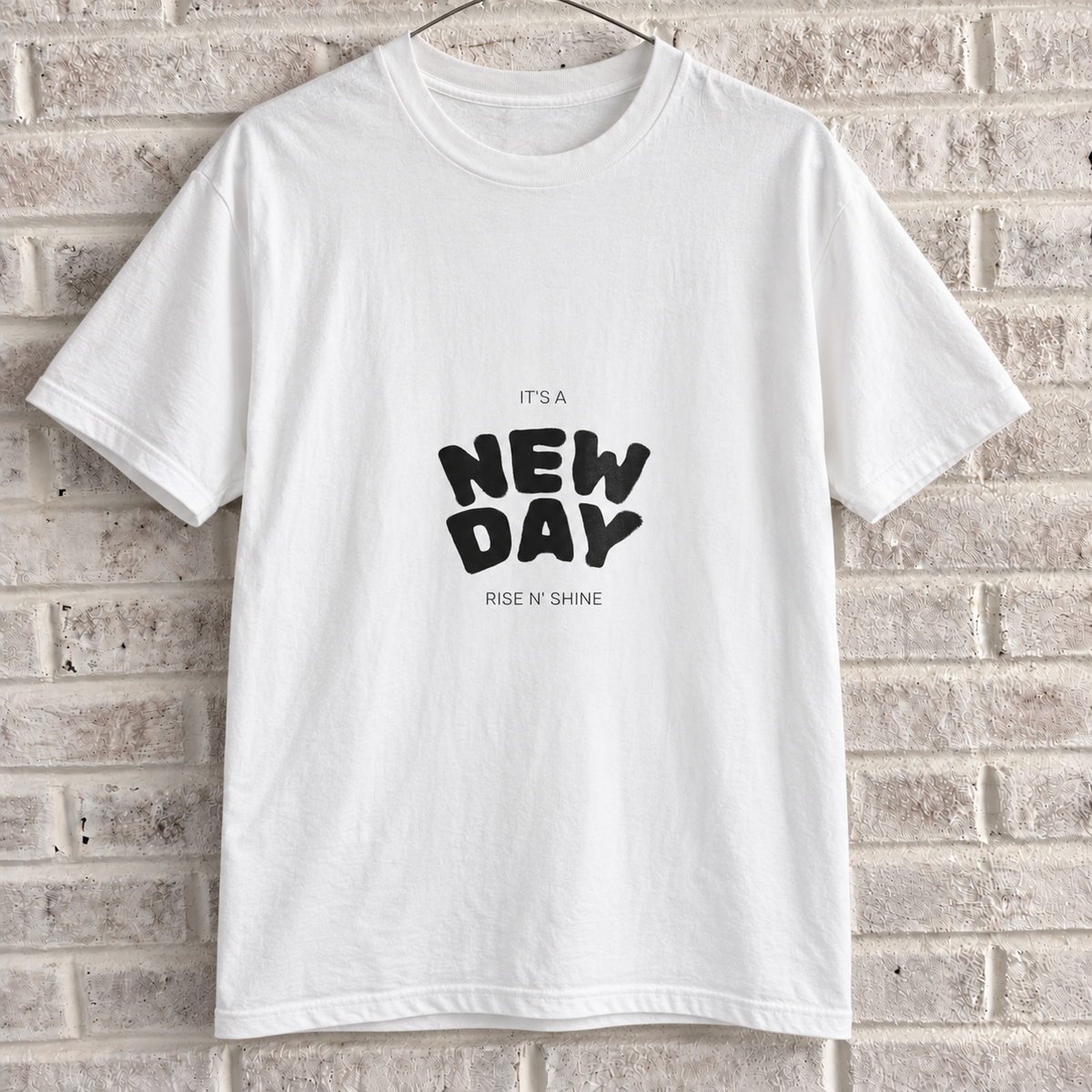 White Comfort Colors graphic tee on a white brick wall with a wire hanger — front view